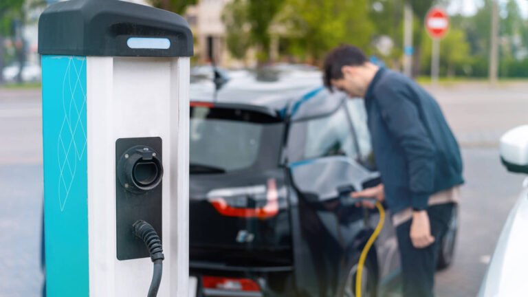 enov.man-plugging-charger-into-electric-car-charge-station-2